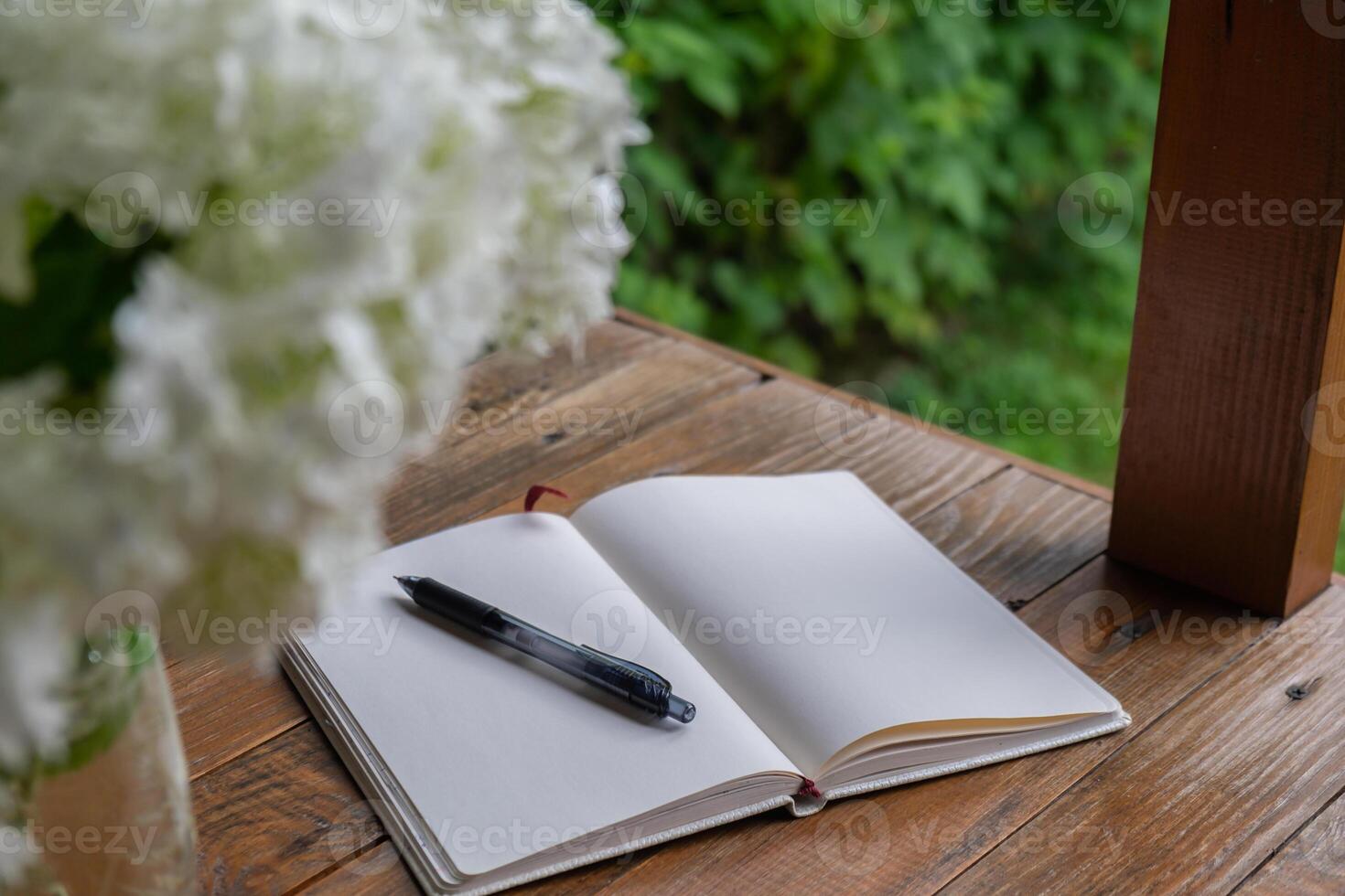 Empty white open paper notebook in wooden table outdoors in garden. Concept of self reflection discovery journal, writing gratitude journal photo