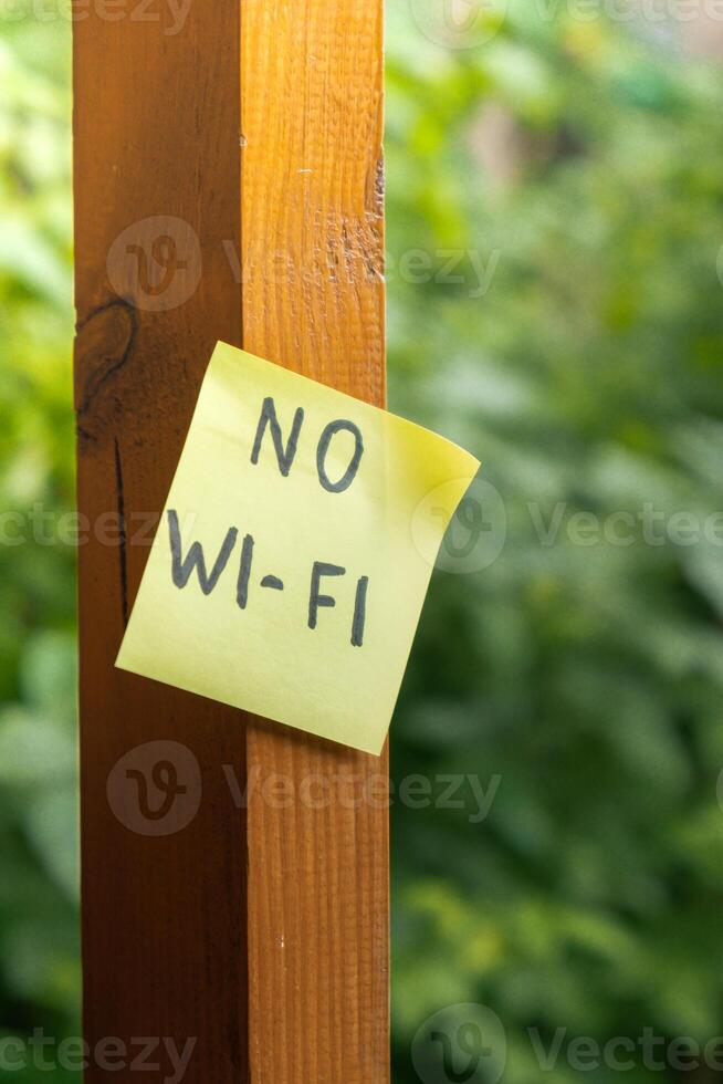 Paper note with text NO WI FI in wooden greenery garden background. Concept of digital detox, unplugging from technology break. Mindful living without gadgets photo