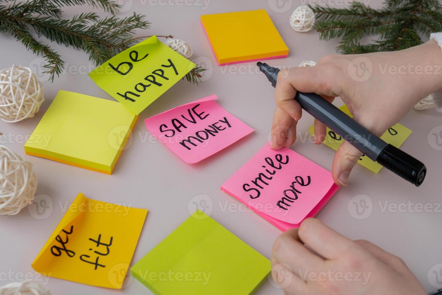 Unrecognizable woman writing new year's resolutions on colorful sticky notes. Making promises for new year, setting goals. Creating vision board motivation photo