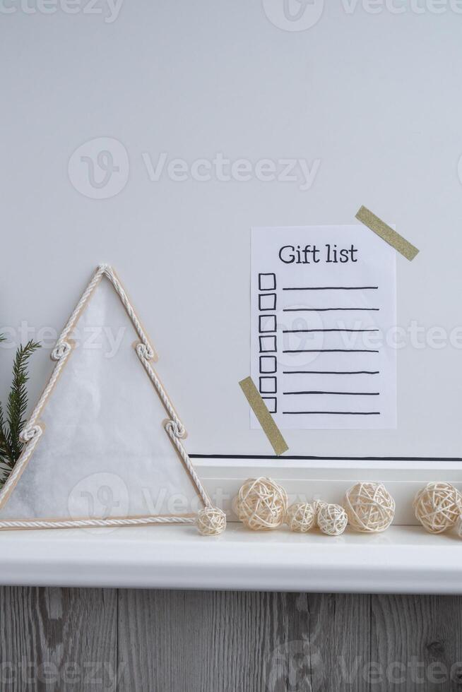 Holiday preparation paper note with GIFT LIST checklist text. Vision board wall with cozy minimalistic handmade new year Christmas decor Low key festive celebration concept photo