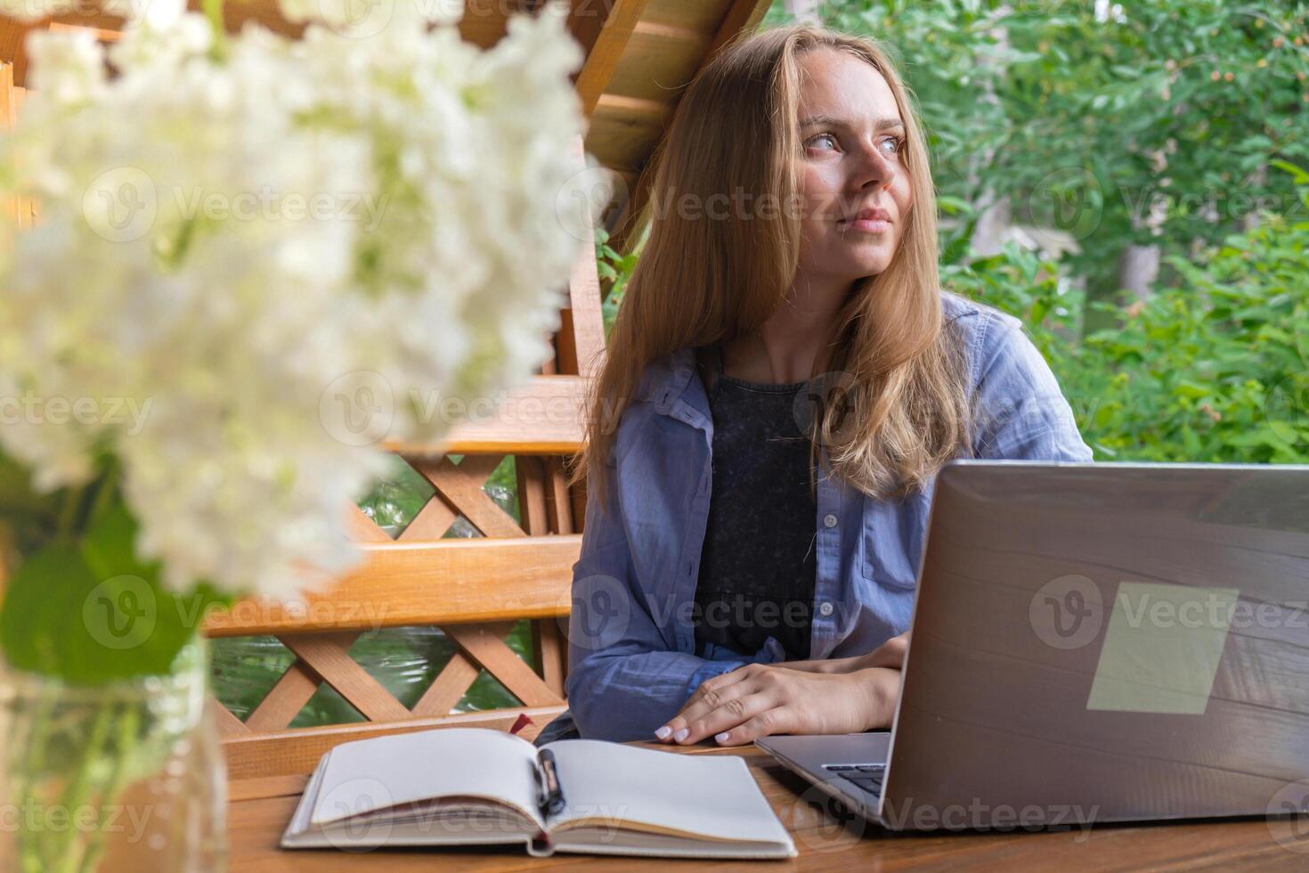 Young woman freelancer working online using laptop and enjoying the beautiful nature outdoors in garden. Online meeting education. Worcation, work from vacation, hybrid work model photo