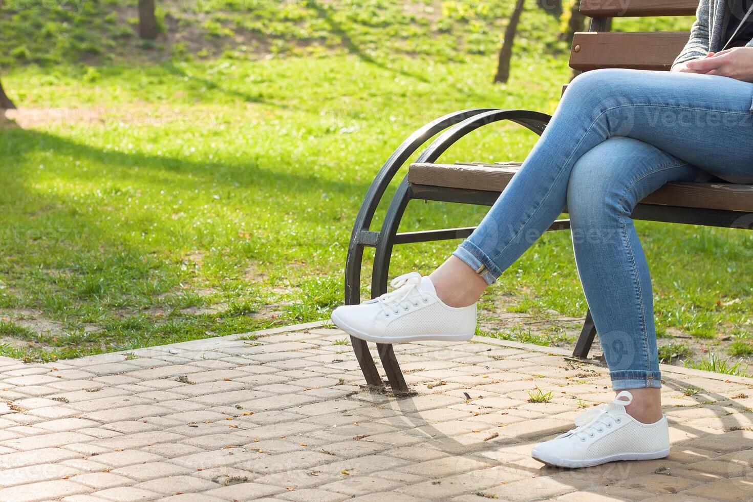 White sneakers on girl legs in blue jeans photo