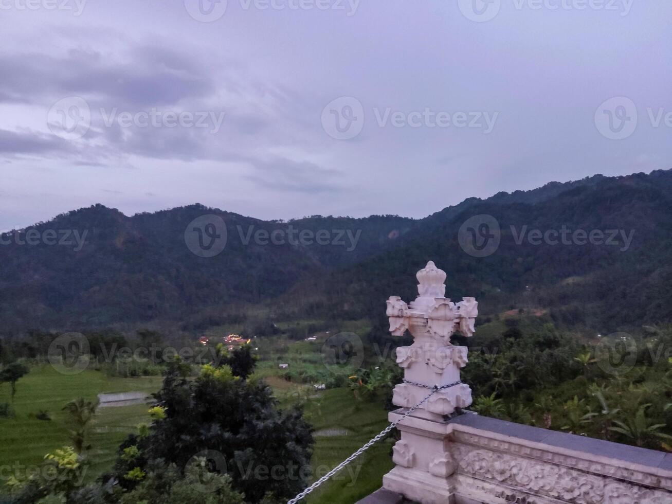 a statue on a balcony overlooking the mountains photo
