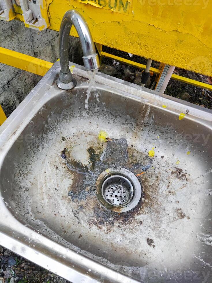 a dirty sink with a yellow faucet photo