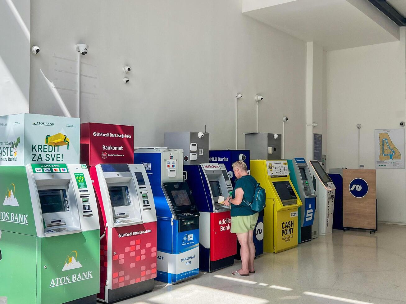 A row of ATMs in a shopping mall. Woman withdrawing money from an ATM photo