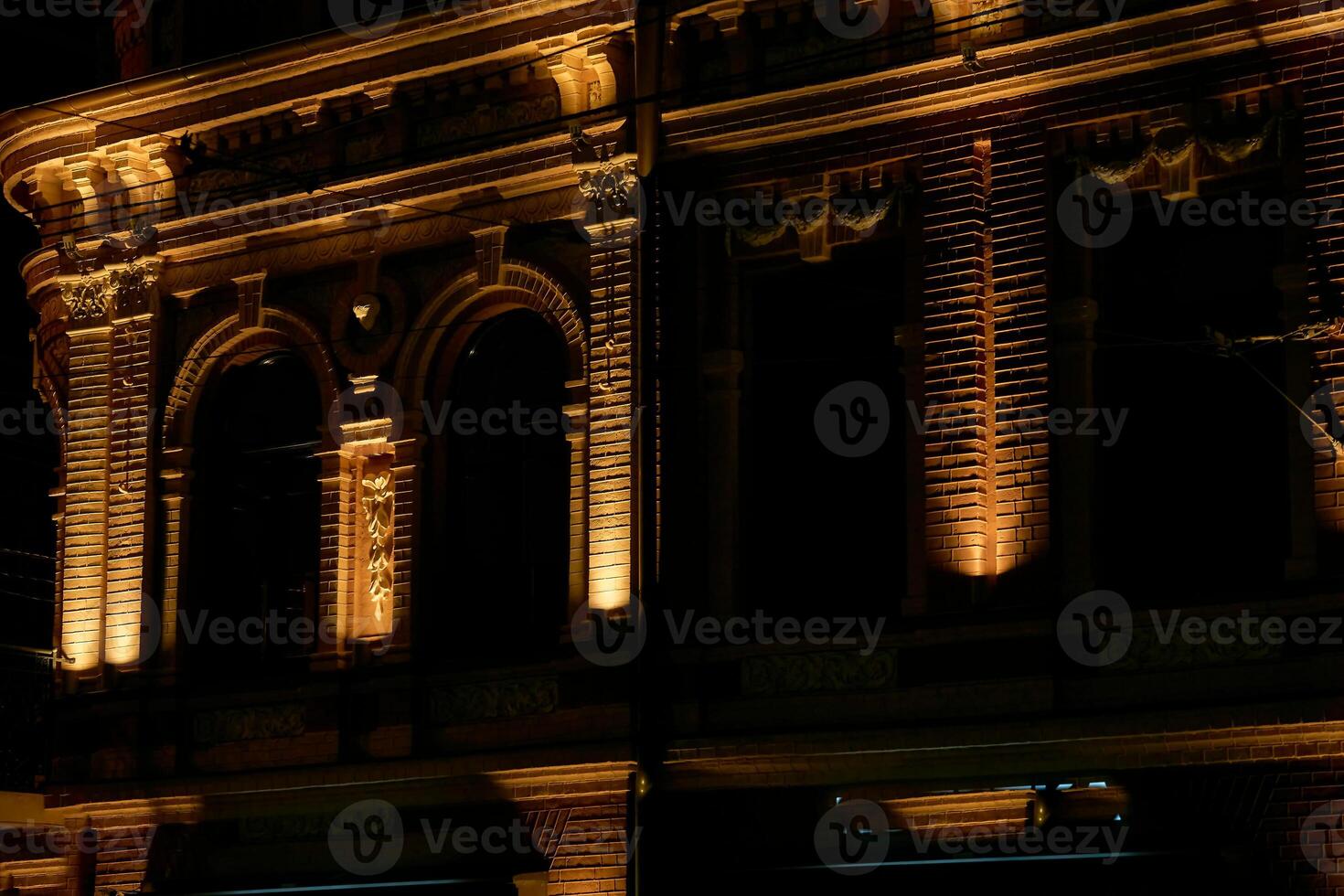 Facade of an old building illuminated with yellow light at night photo
