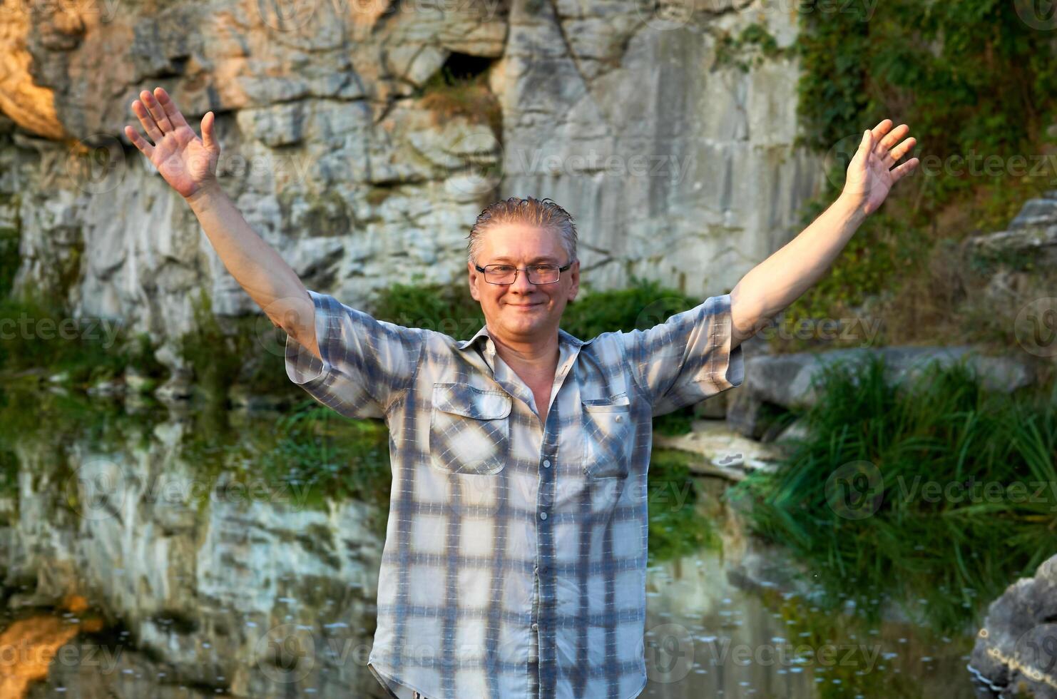 Cheerful smiling man tourist stands on a mountain river canyon photo