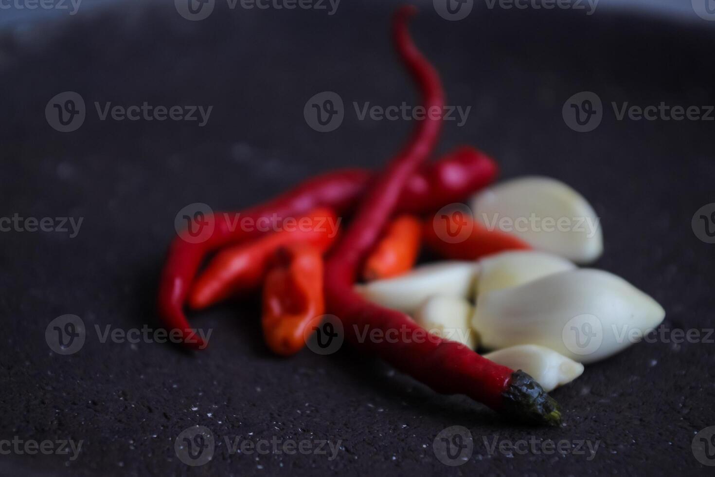 a pile of chilies and onions on a stone mortar and pestle to grind the ingredients for making traditional chili sauce. Traditional Indonesian sambal or chili sauce. photo