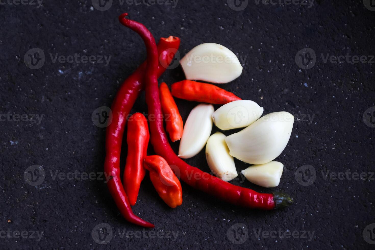 a pile of chilies and onions on a stone mortar and pestle to grind the ingredients for making traditional chili sauce. Traditional Indonesian sambal or chili sauce. photo