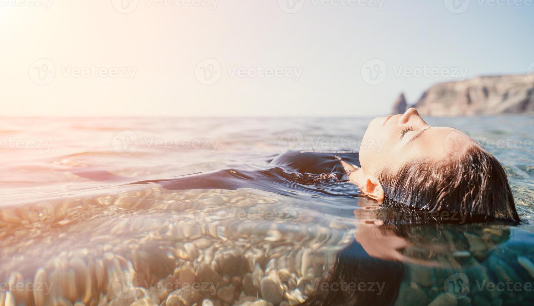 Woman swimming in sea at sunset, float on calm water back view. Concept of body image and fitness, enjoying a serene beach. Happy woman with perfect fit body enjoys sea beach photo