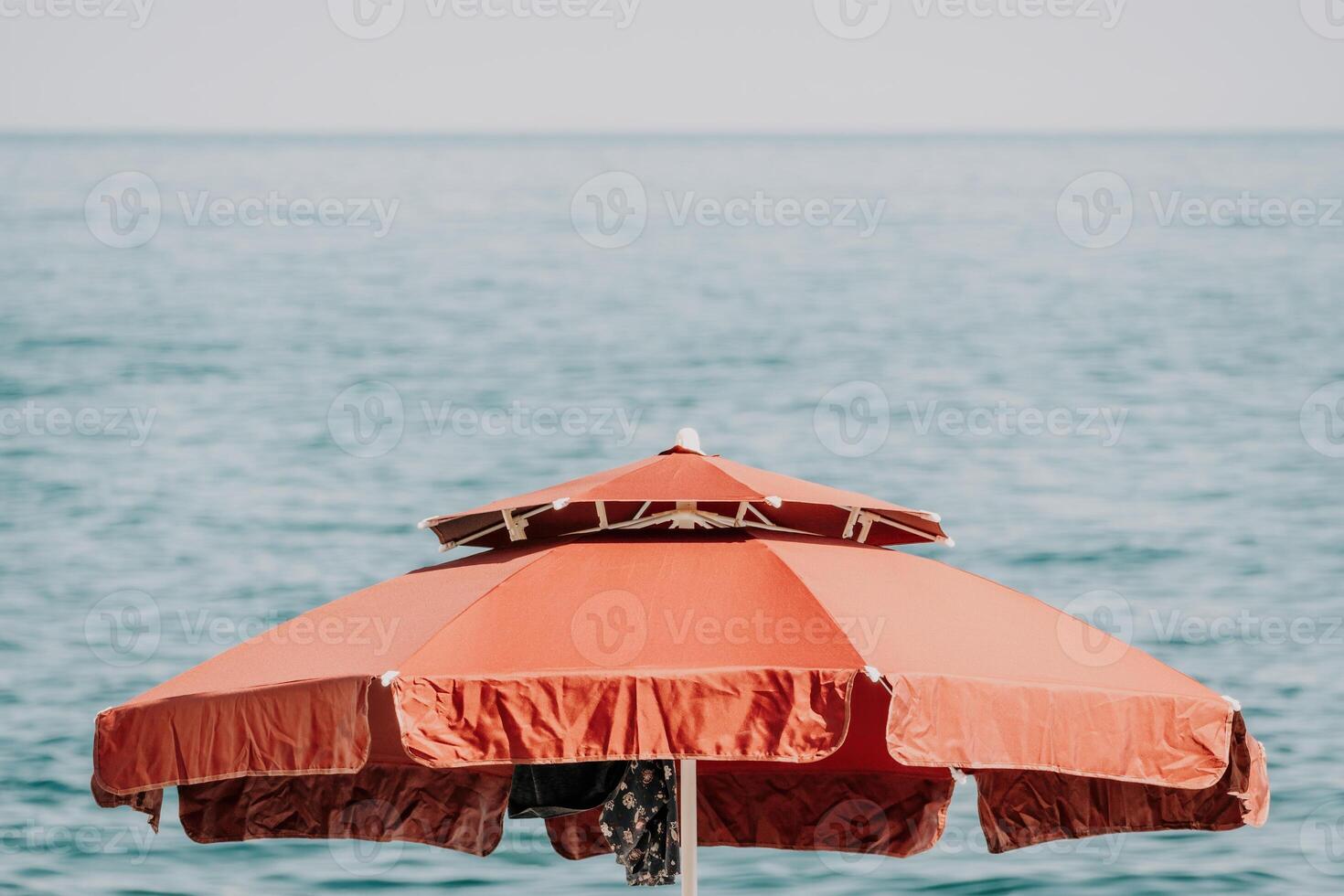 Red Beach Umbrella on the Background of the Blue Sea Ocean. Beach Landscape. Summer travel and holidays concept. photo
