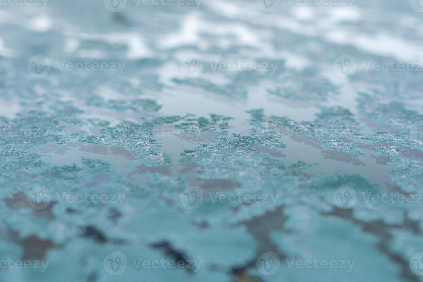 Selective focus. First frost on a frozen car, late autumn close-up. Beautiful abstract frozen microcosmos pattern. Freezing weather frost action in nature. Winter backdrop. photo