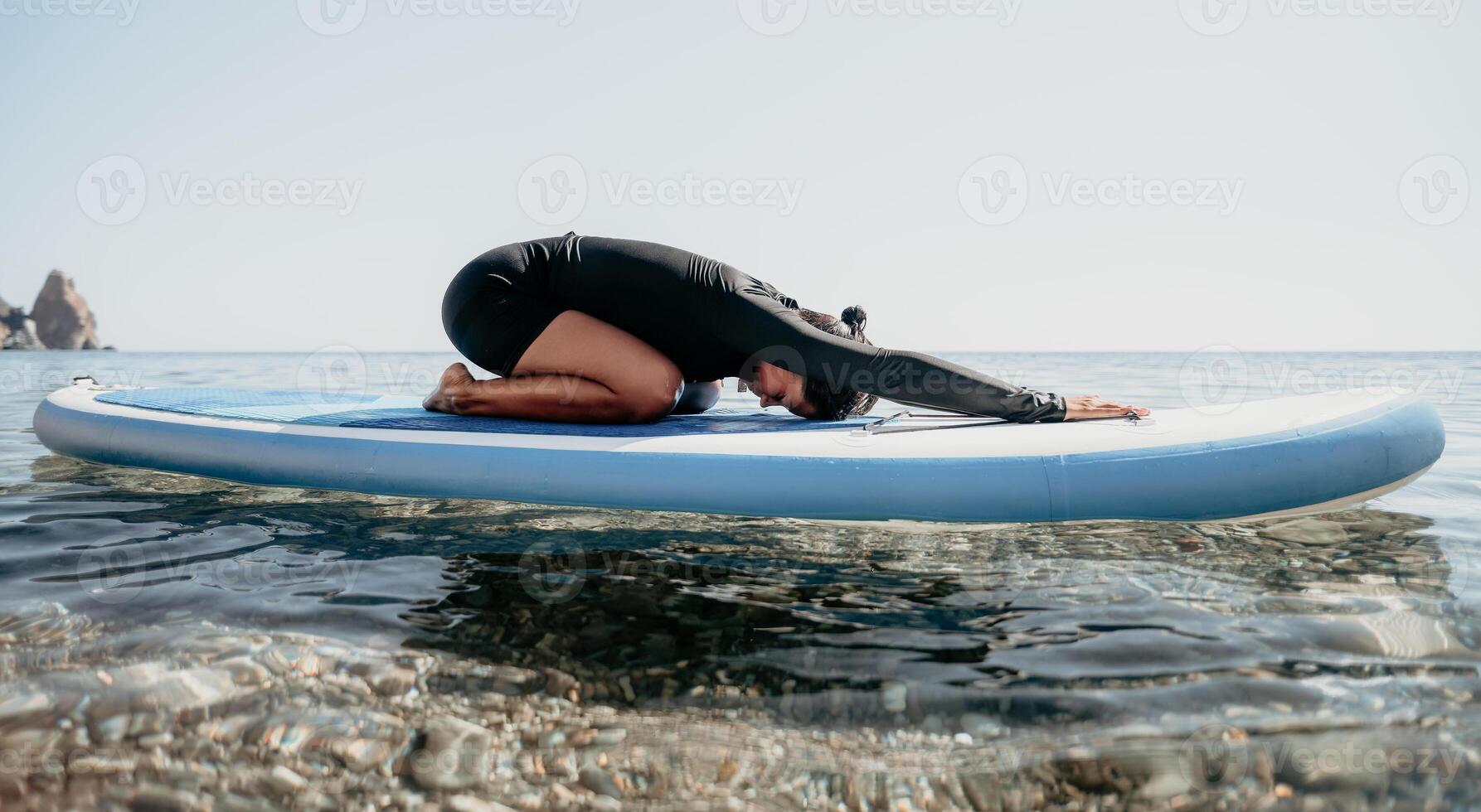 Woman sup yoga. Happy sporty woman practising yoga pilates on paddle sup surfboard. Female stretching doing workout on sea water. Modern individual female hipster outdoor summer sport activity. photo