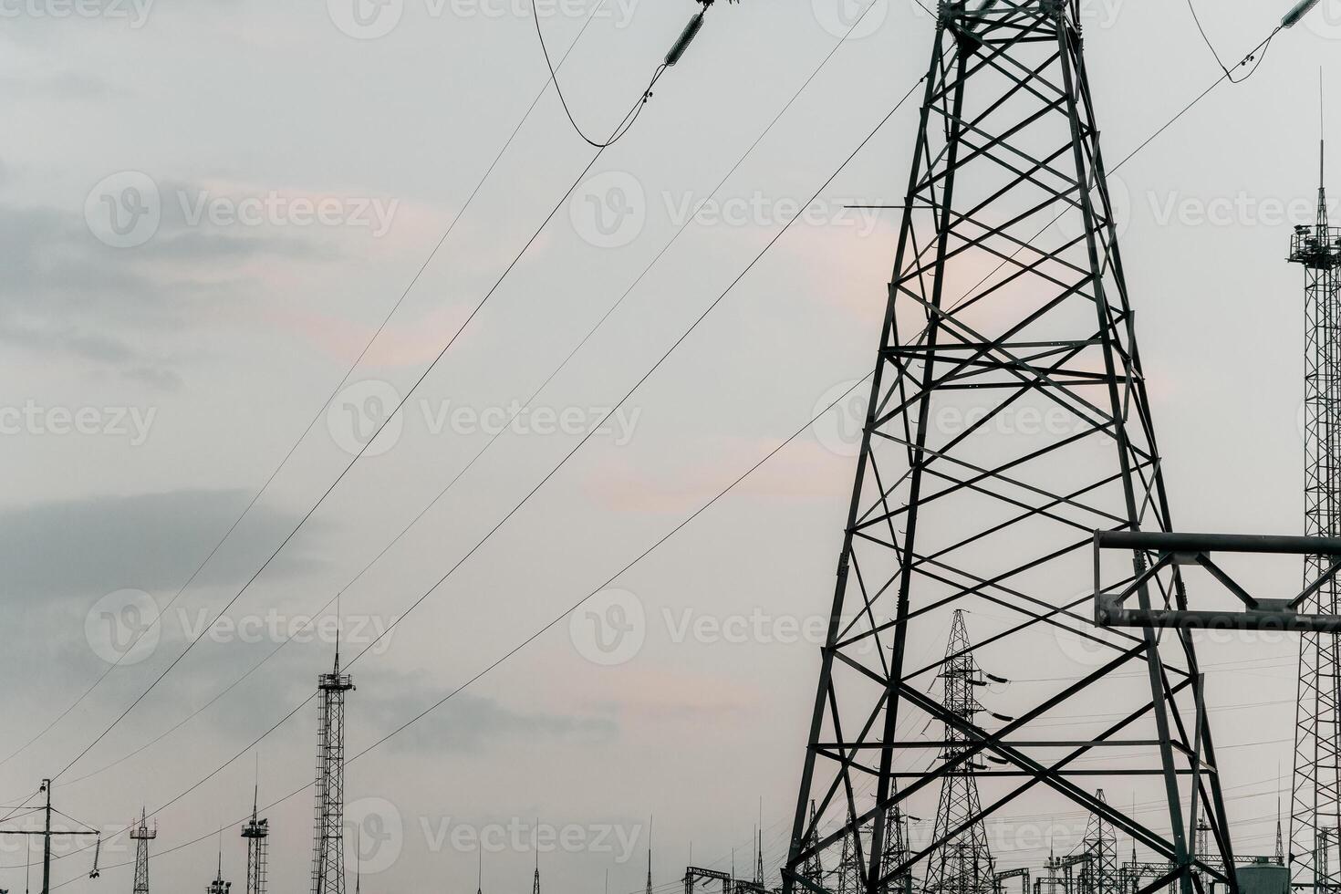 High voltage electric distribution network at sunset. Power transmission lines on supports with ceramic insulators and transformers at large electrical distribution substation photo