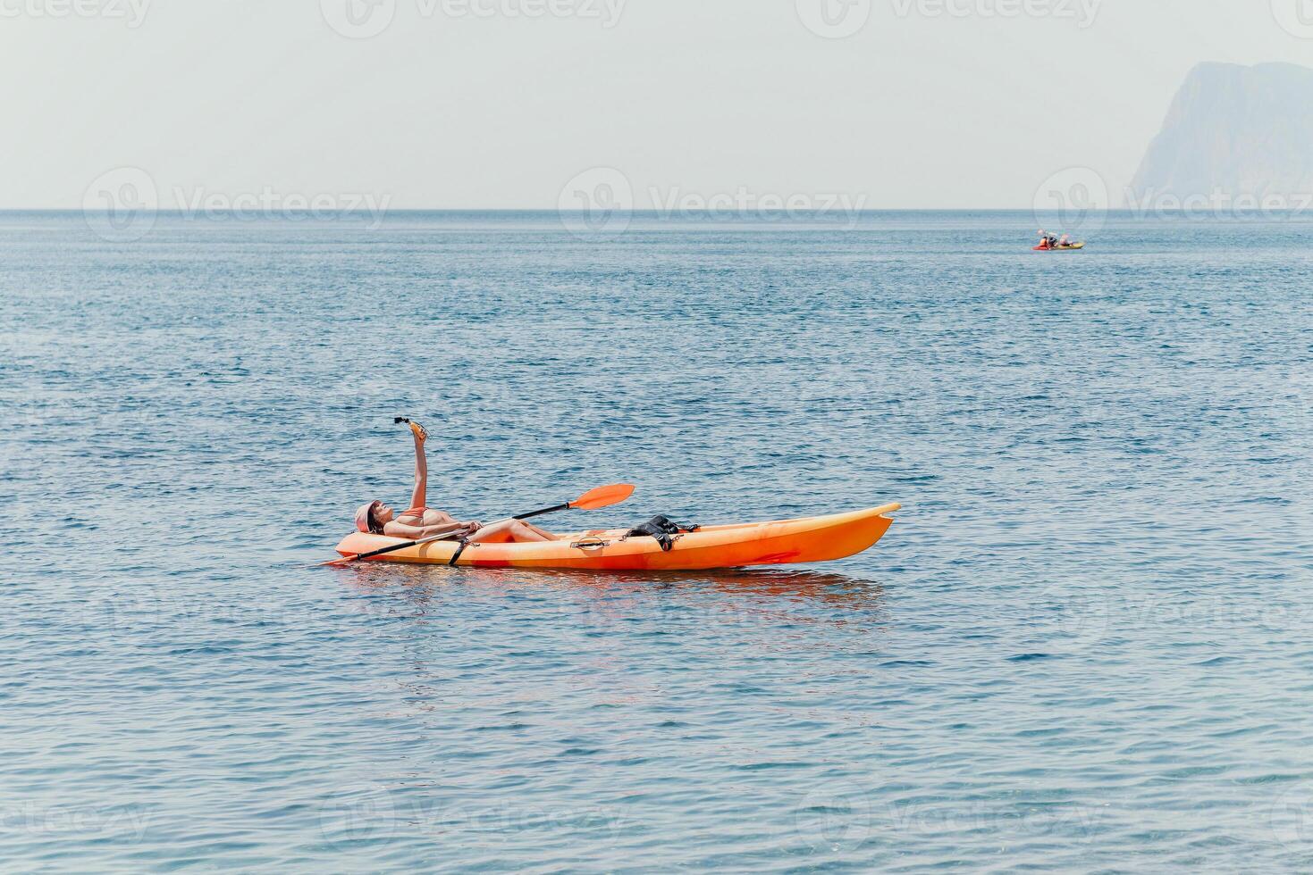 Woman sea kayak. Happy smiling woman paddling in kayak on ocean. Calm sea water and horizon in background. Active lifestyle at sea. Summer vacation. photo