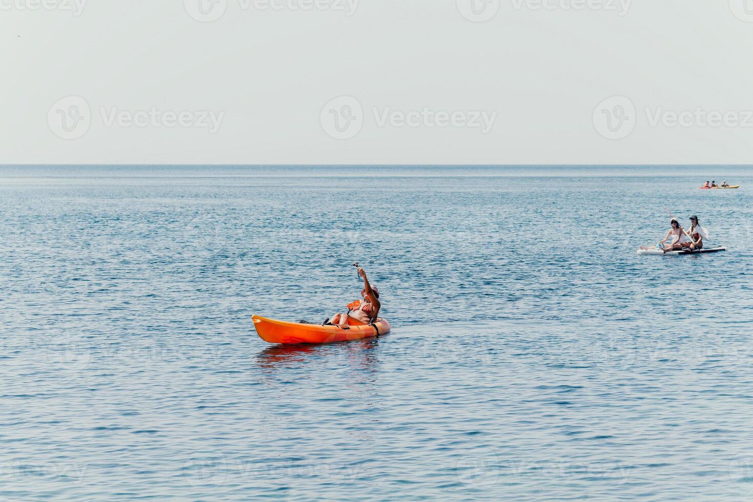 Woman sea kayak. Happy smiling woman paddling in kayak on ocean. Calm sea water and horizon in background. Active lifestyle at sea. Summer vacation. photo