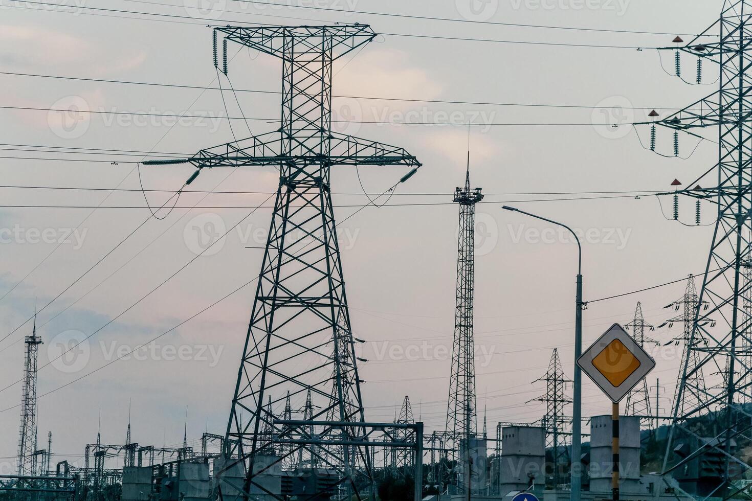High voltage electric distribution network at sunset. Power transmission lines on supports with ceramic insulators and transformers at large electrical distribution substation photo