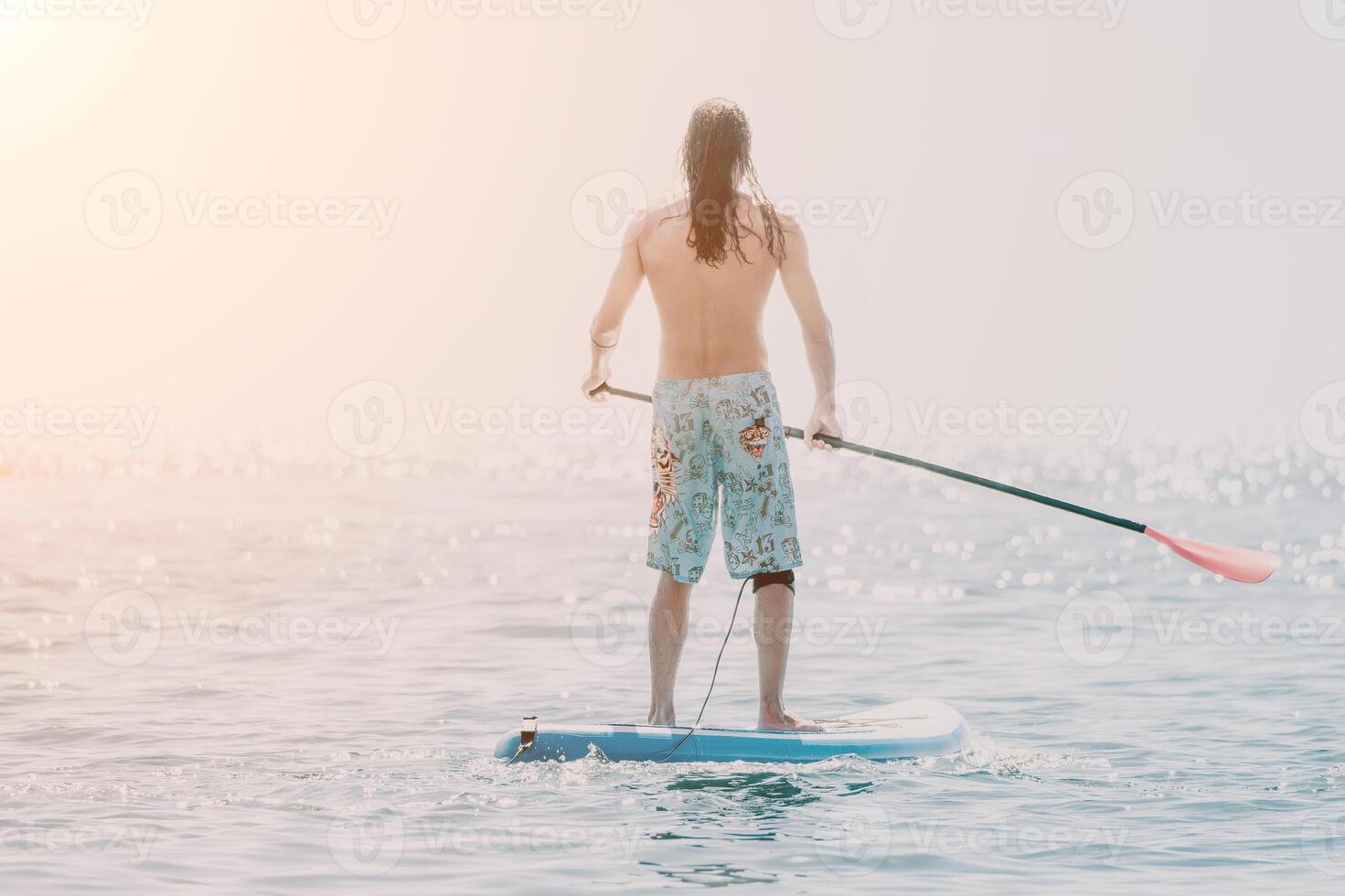 Man Sup Sea. Strong athletic man learns to paddle sup standing on board in open sea ocean on sunny day. Summer holiday vacation and travel concept. Aerial view. Slow motion photo