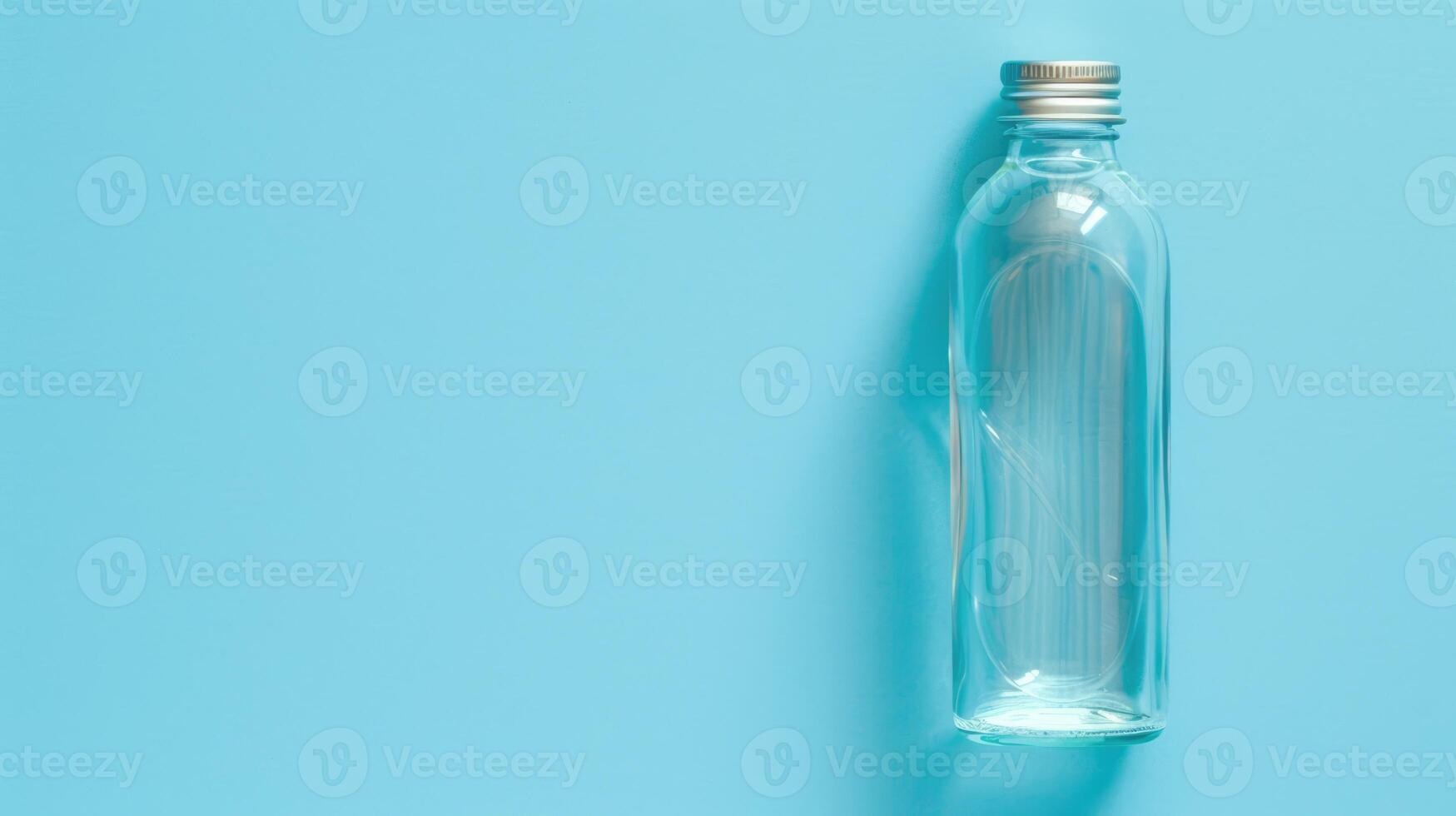 Empty glass bottle with a cap on blue background with copy space photo