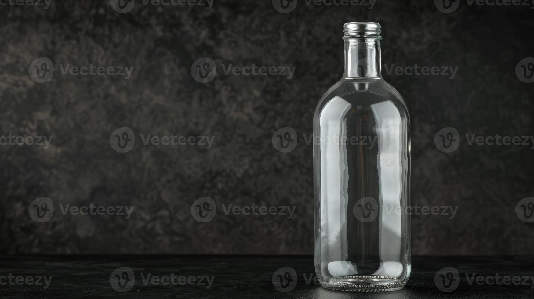 Empty glass bottle on black background with copy space photo