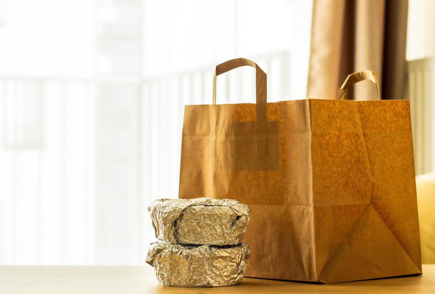 package of food from delivery stands on the table, containers with hot food packed in foil and sushi, food delivery concept photo