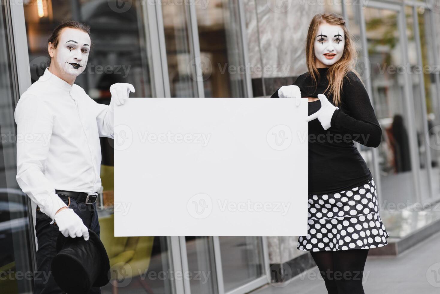 Your text here. Actors mimes holding empty white letter. Colorful portrait with gray background. April fools day photo