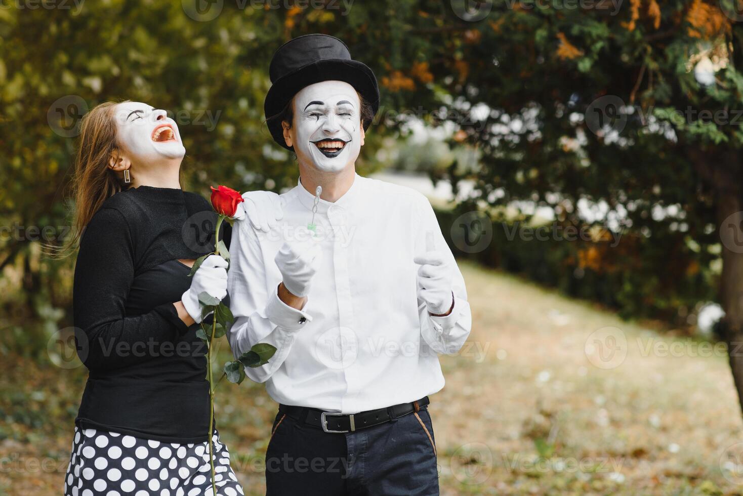 Mime artist blowing a bubble through wand on green background photo