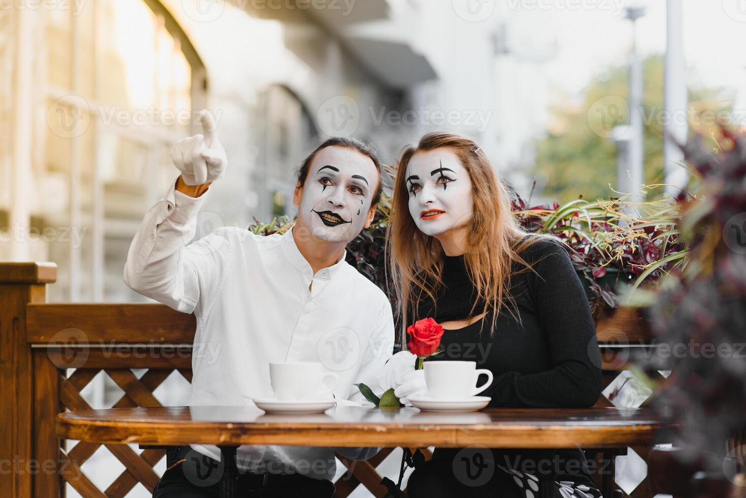 mime guy and girl in cafe drinking coffee. Mime in front of Paris cafe acting like drinking tea or coffee. photo