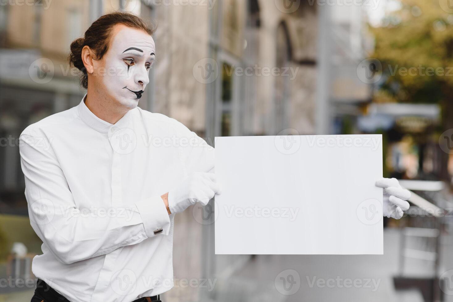 Your text here. Actor mime holding empty white letter. Colorful portrait with gray background. April fools day photo