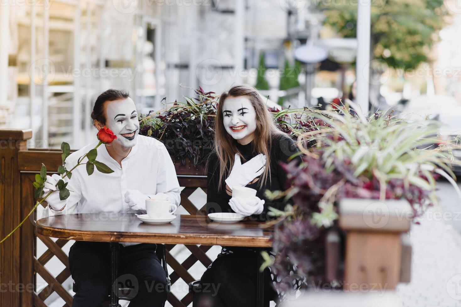 mime guy and girl in cafe drinking coffee. Mime in front of Paris cafe acting like drinking tea or coffee. photo