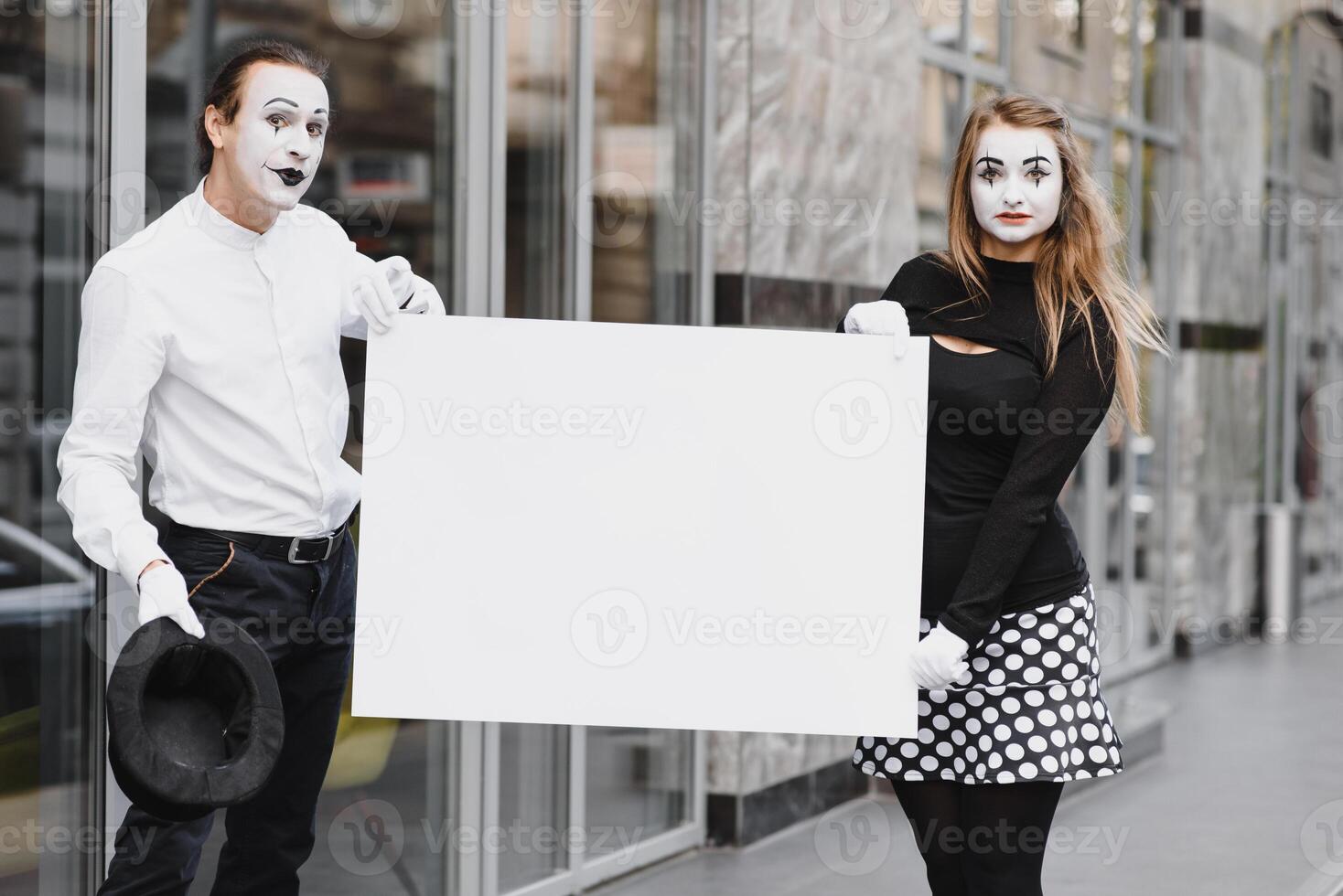 Your text here. Actors mimes holding empty white letter. Colorful portrait with gray background. April fools day photo
