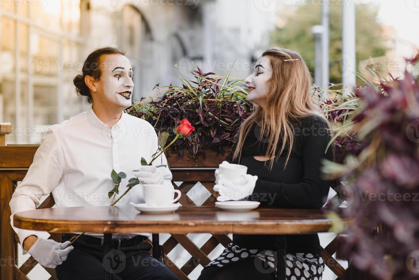 mime guy and girl in cafe drinking coffee. Mime in front of Paris cafe acting like drinking tea or coffee. photo
