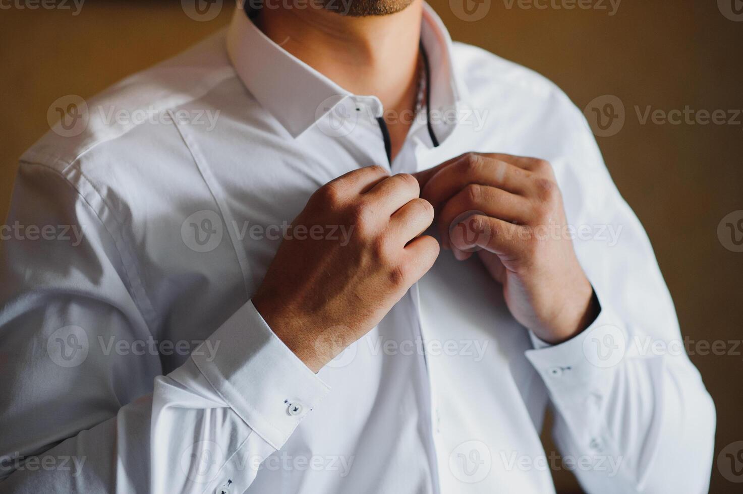 A businessman dresses a white shirt close-up, the groom prepares for the wedding ceremony. Male style. Shirts and collar cuffs photo