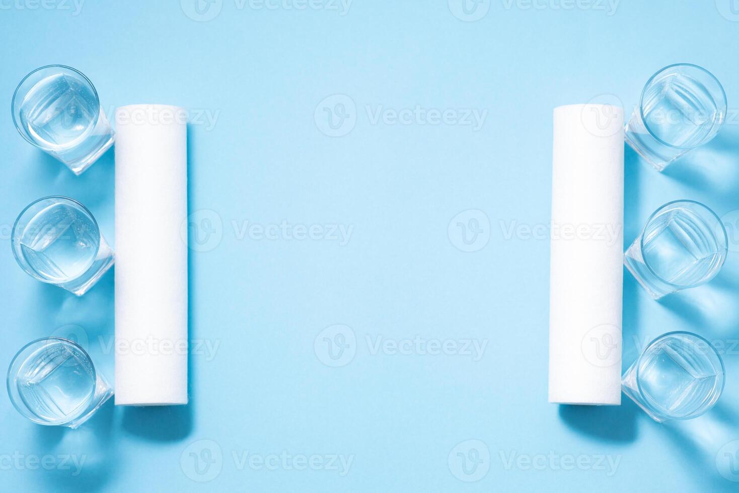 Glasses of dirty and clear water and filter cartridges to domestic water treatment systems at bright blue background. Concept of water treatment. photo