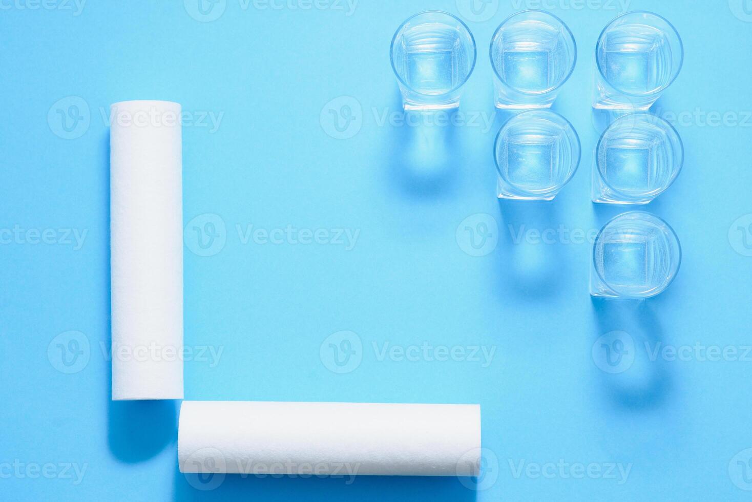 Water filters. Carbon cartridges and glasses on a blue background. Household filtration system. photo