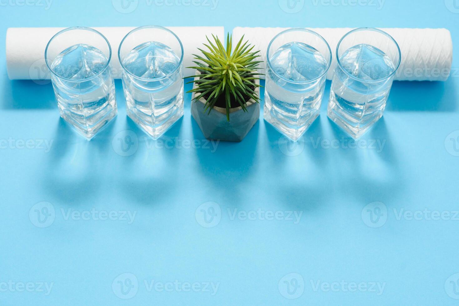 Water filters. Carbon cartridges and a glasses on a blue background. Household filtration system. photo