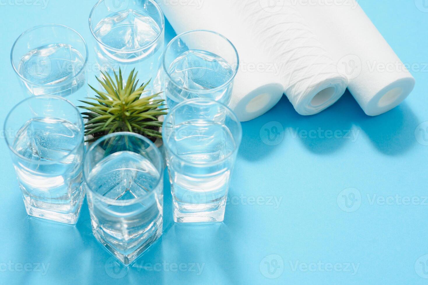 Water filters. Carbon cartridges and a glasses on a blue background. Household filtration system. photo