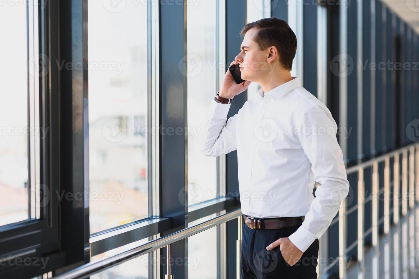 Business man in suit talking on phone and looking away near the window. photo