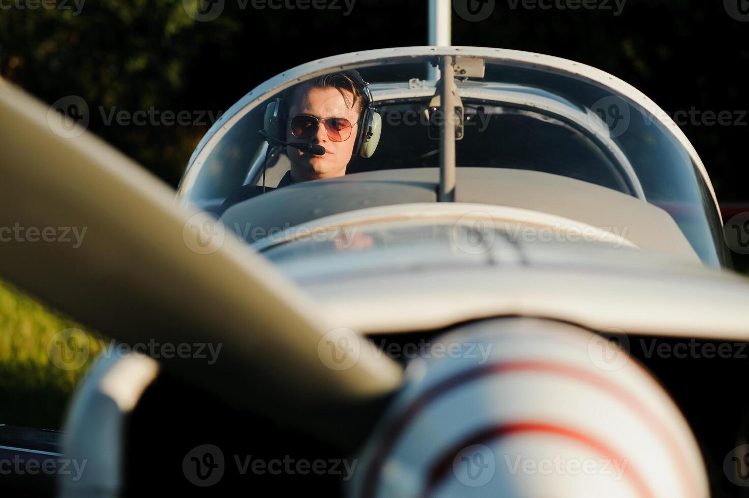 Smiling attractive young man pilot sitting in cabin of small aircraft photo