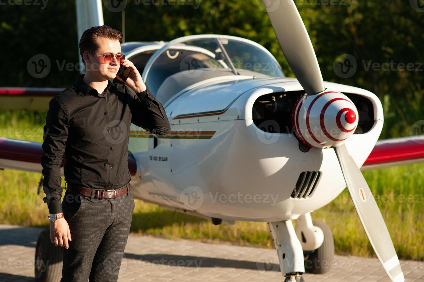 Business man with his airplanes. He is walking in the airport with the smart phone and making a call. photo