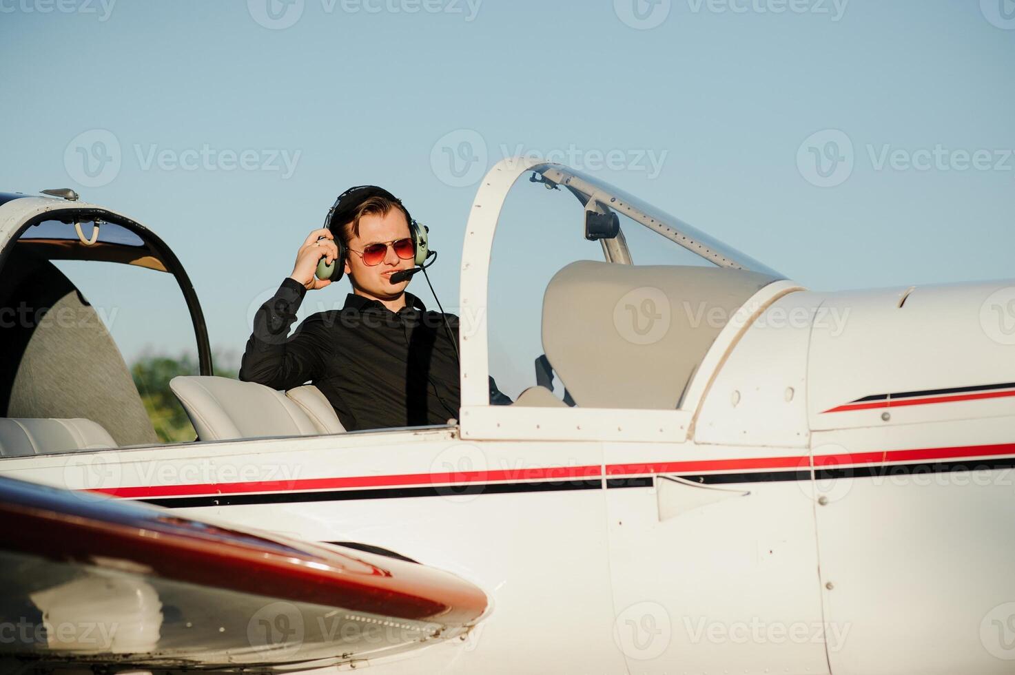 Portrait of confident young man pilot in small plane photo