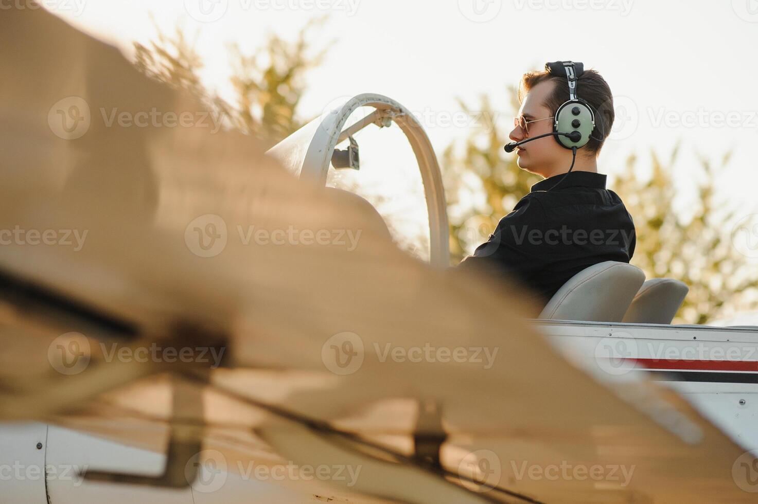Smiling attractive young man pilot sitting in cabin of small aircraft photo