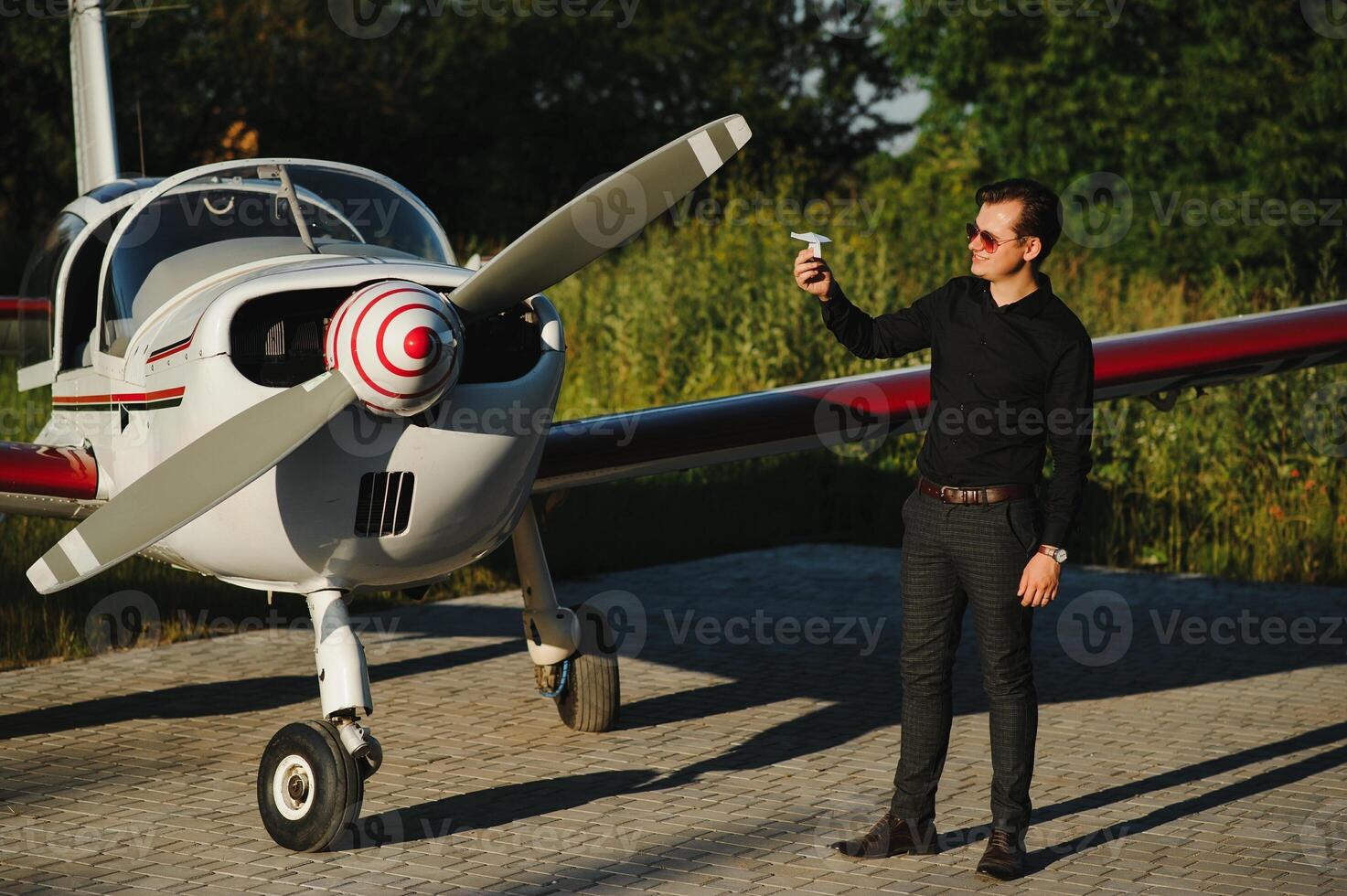 Pensive attrative young man pilot standing near small aircraft photo