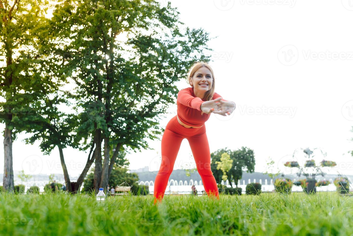 Young female workout before fitness training session at the park. Healthy young woman warming up outdoors. She is stretching her arms and looking away,hi key. photo