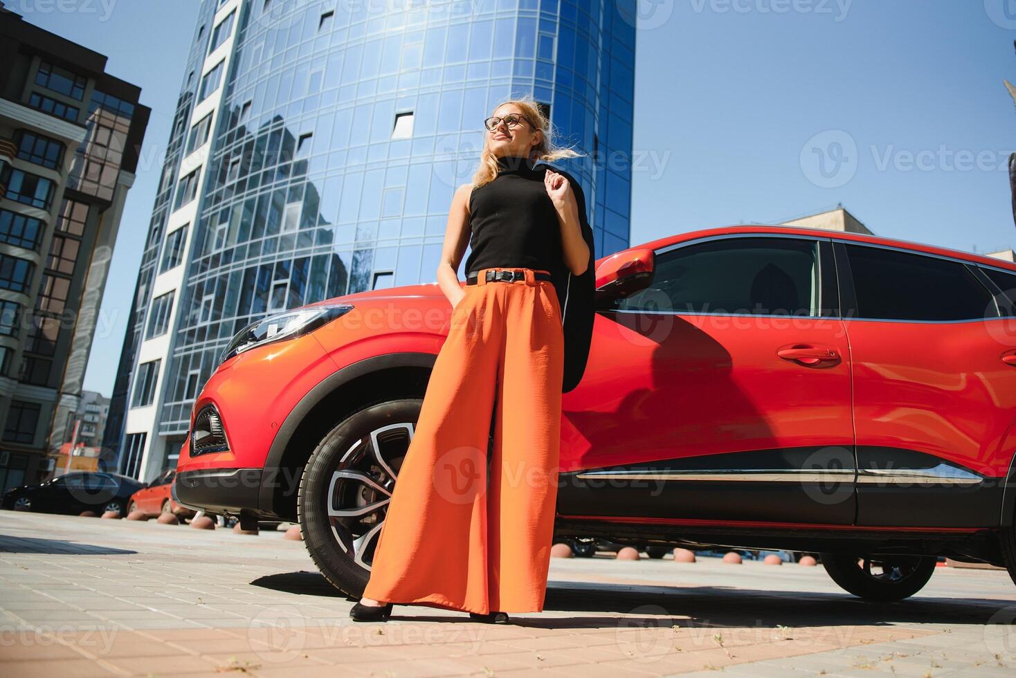 Yong pretty woman standing near a big all terrain car outdoors. Driver girl in casual clothes outside her vehicle. photo