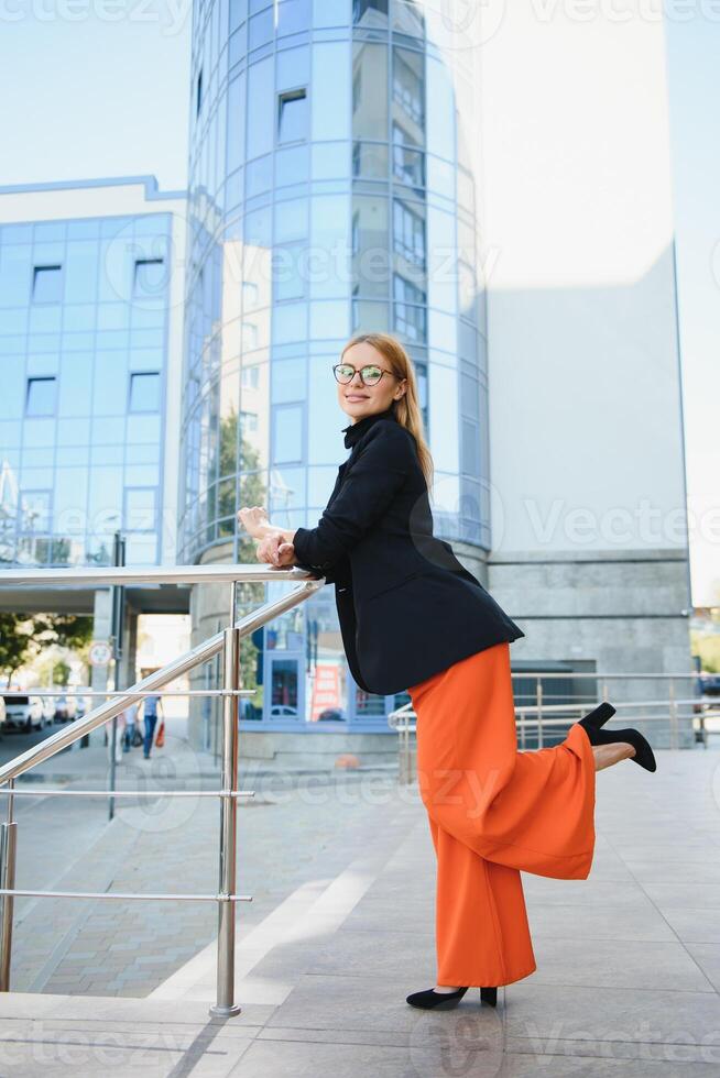 business woman on the street is looking at a document. Scrolls a folder near the building. photo