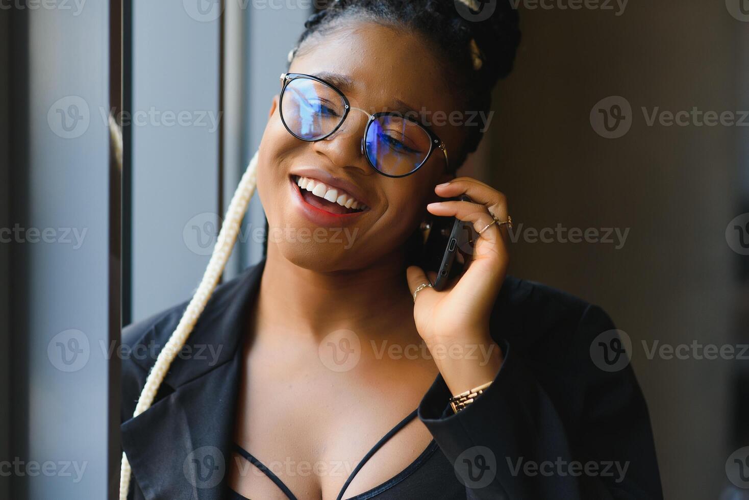 Smiling dark skinned woman in trendy wear laving cafe talking on mobile phone via roaming tariffs,african american millennial female walking and making smartphone call satisfied with connection photo