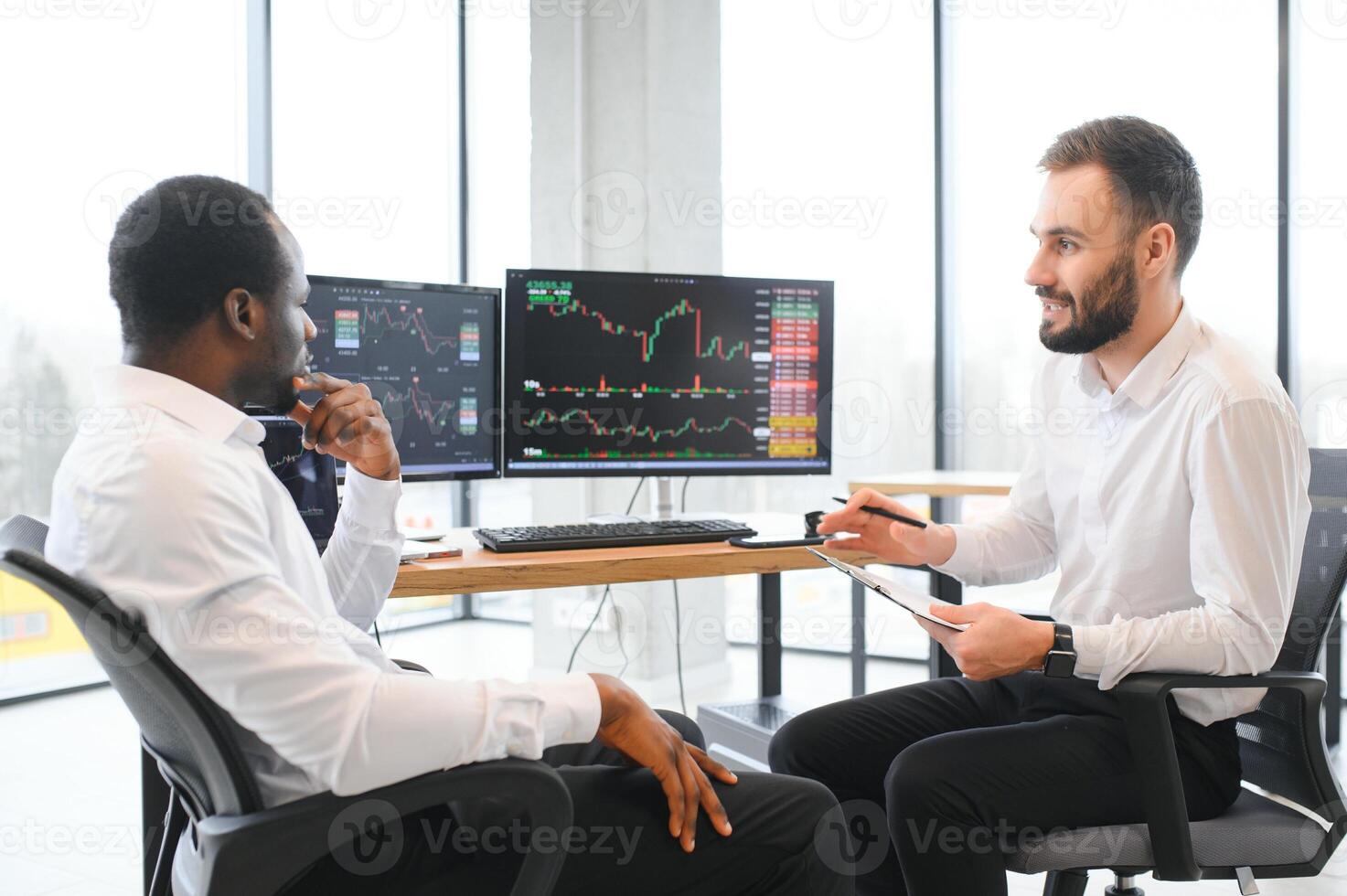 Two confident businessmen, financial analysts or investment advisers sitting at office desk photo