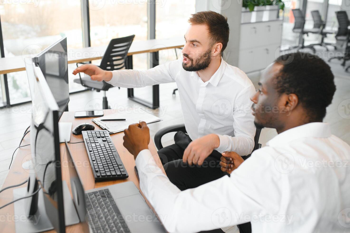 Two successful trader sitting in office, checking cryptocurrency information data on finance market graph, pointing on monitor photo