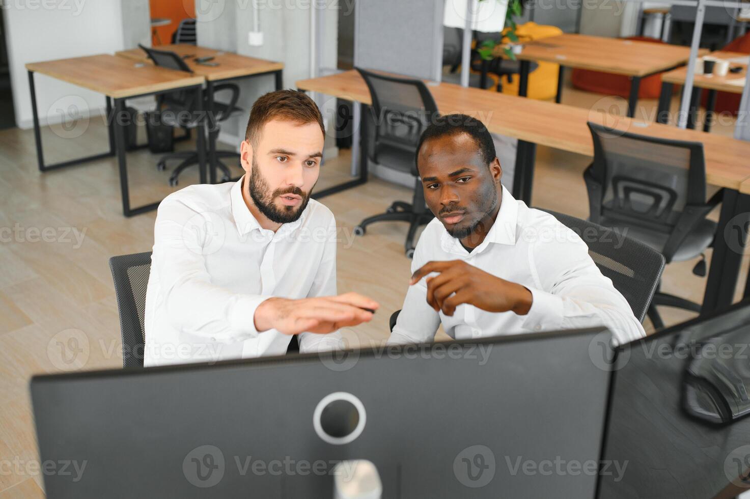 Two successful trader sitting in office, checking cryptocurrency information data on finance market graph, pointing on monitor photo